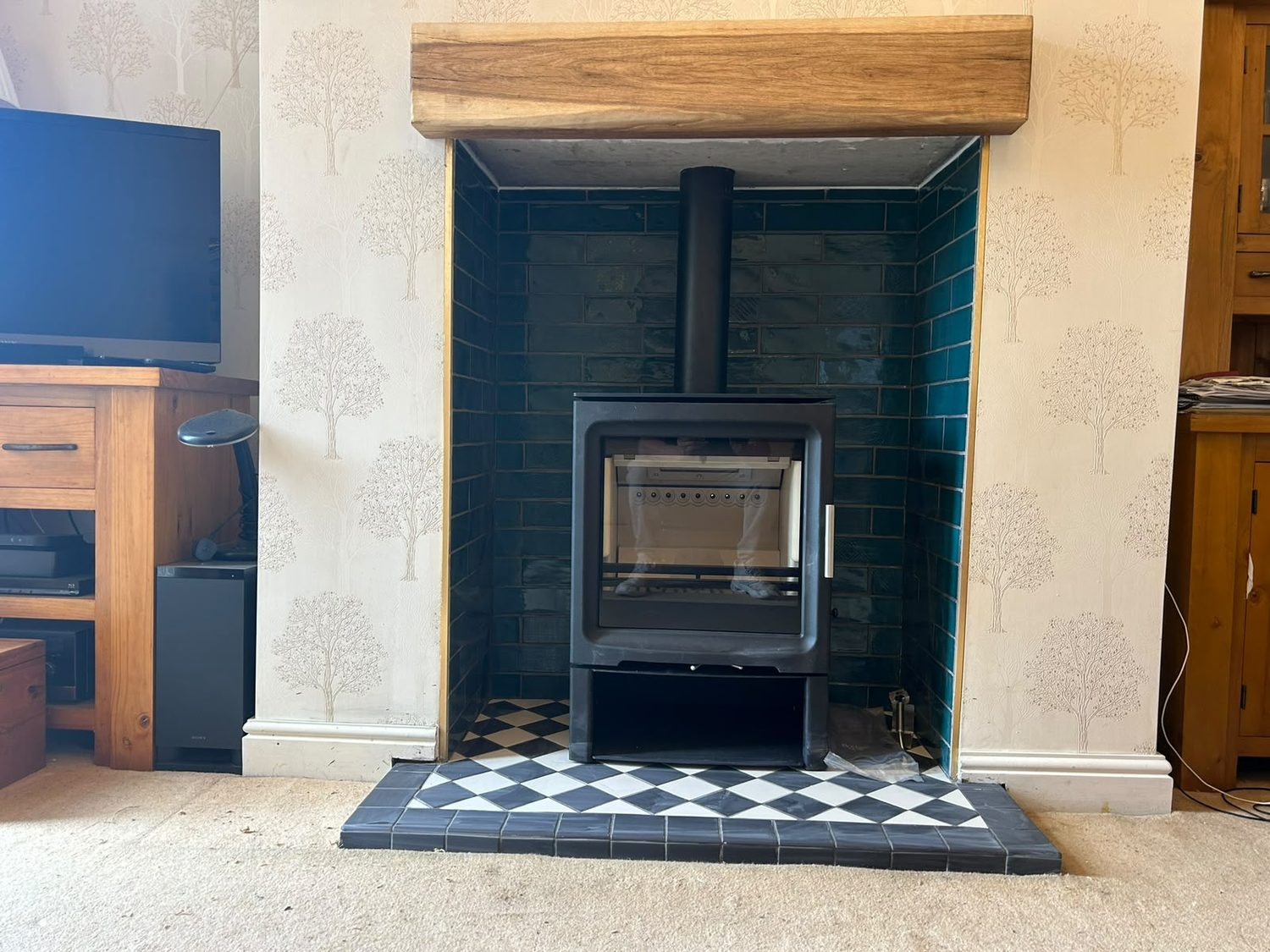 Stove in a teal metro tiled chamber with a harlequin tiled hearth